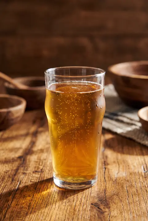 Golden apple cider with fine bubbles in a pint glass