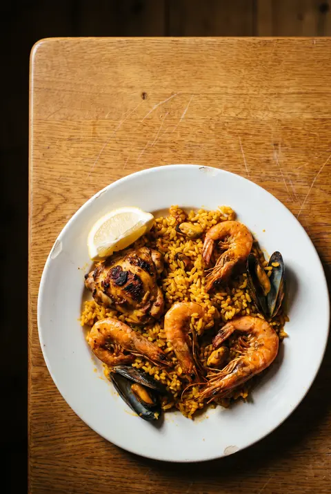 A plate of paella with chicken on a white plate