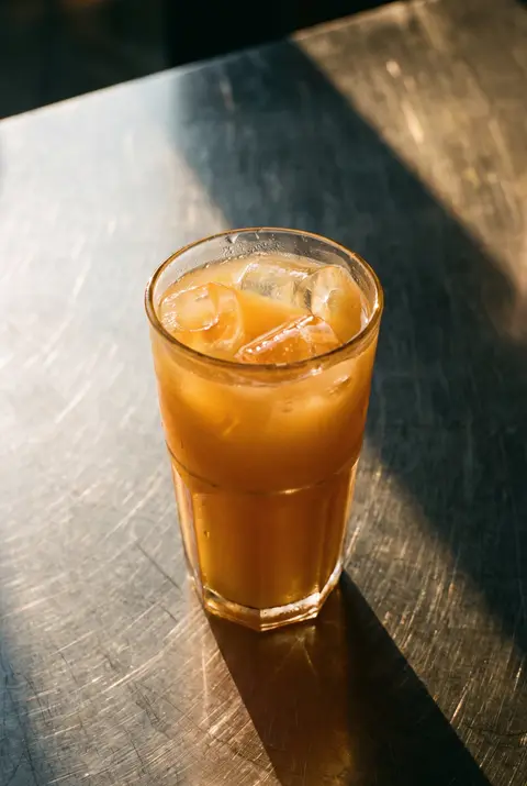 500 ml of cloudy orange mango energy drink with ice in a clear glass