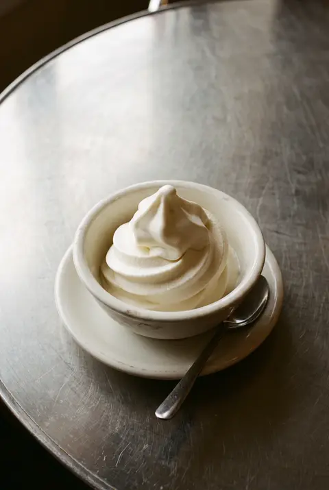 A regular cup of plain white frozen yoghurt on a white plate