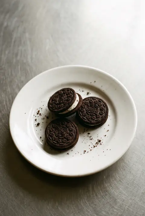 Three dark chocolate sandwich cookies with white cream filling on a white plate