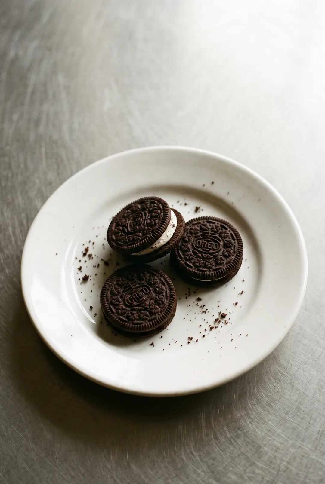 Three dark chocolate sandwich cookies with white cream filling on a white plate
