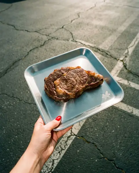 A seared ribeye steak on a steel tray