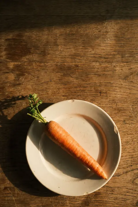 A medium raw carrot on a white plate
