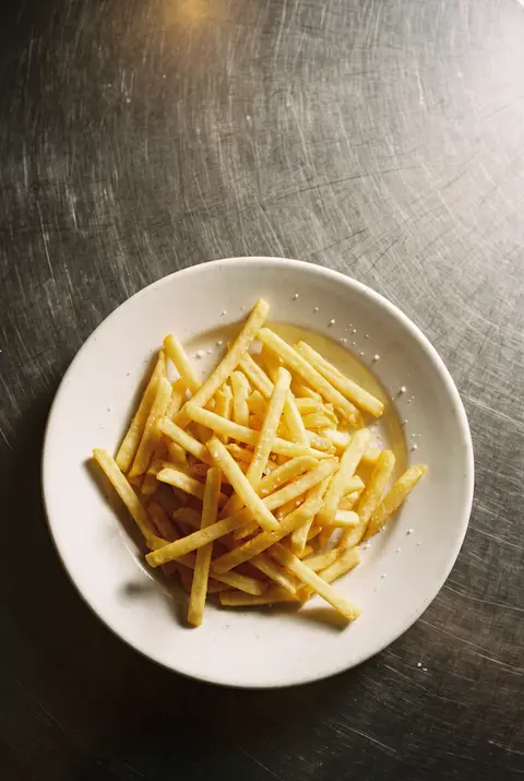 A medium portion of thin golden fast food fries on a white plate