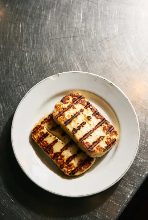 Two thick slices of grilled halloumi with grill marks on a white plate