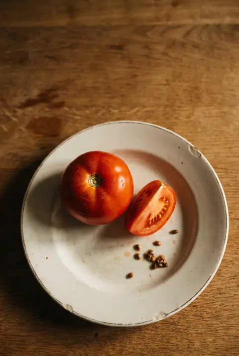A ripe medium tomato on a white plate