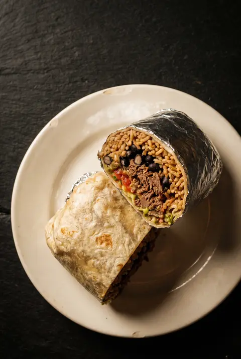 A large restaurant burrito wrapped in a flour tortilla on a white plate