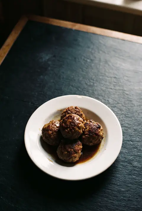 Five beef and pork meatballs on a white plate