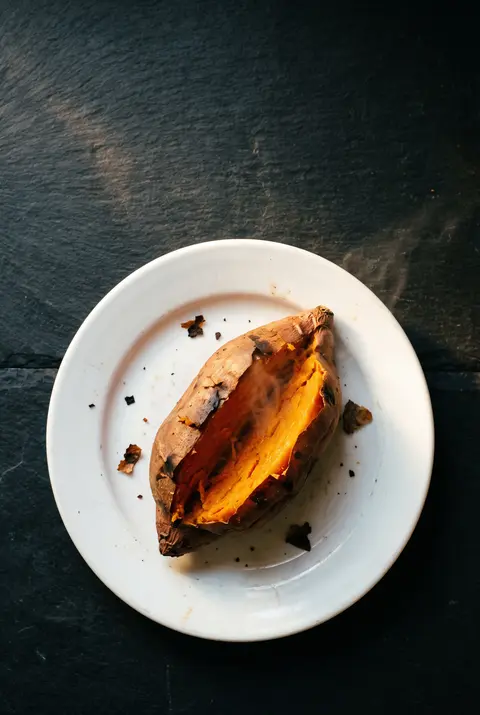 A medium baked sweet potato on a white plate