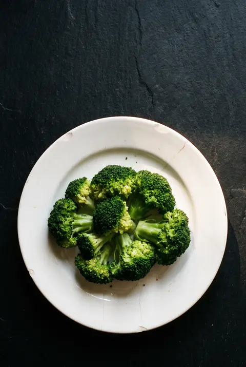 A portion of steamed broccoli florets on a white plate