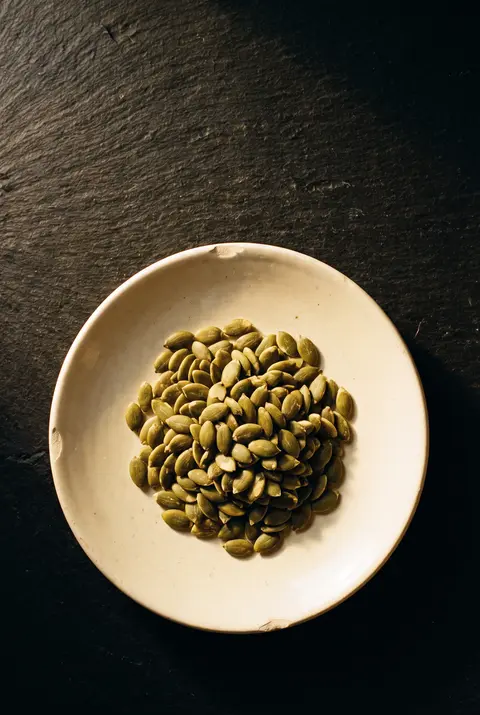 A small heap of green pumpkin seeds on a white plate