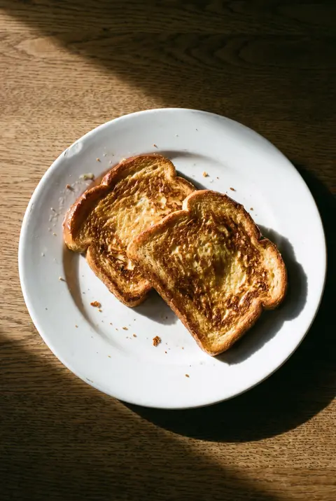 Two slices of French toast fried golden in butter on a white plate