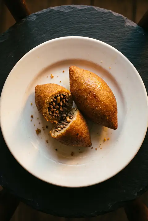 Two fried kibbeh on a white plate