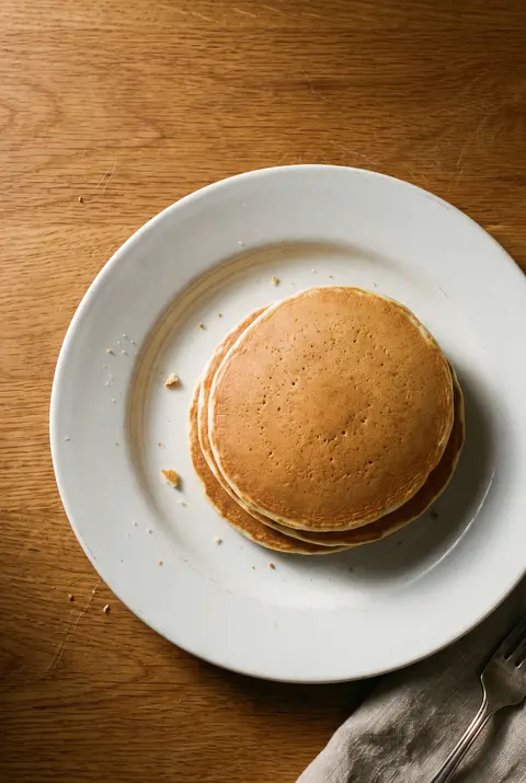 A stack of three plain pancakes on a white plate