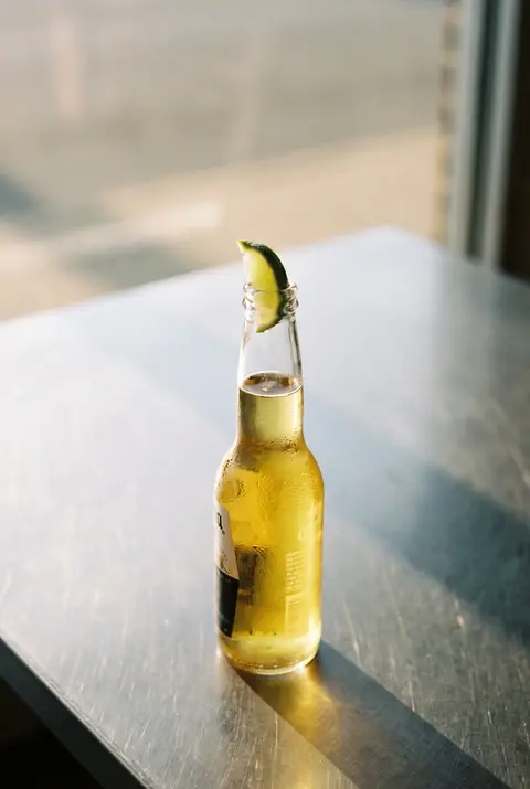 A pale golden lager with a wedge of lime in the neck in a clear long neck bottle