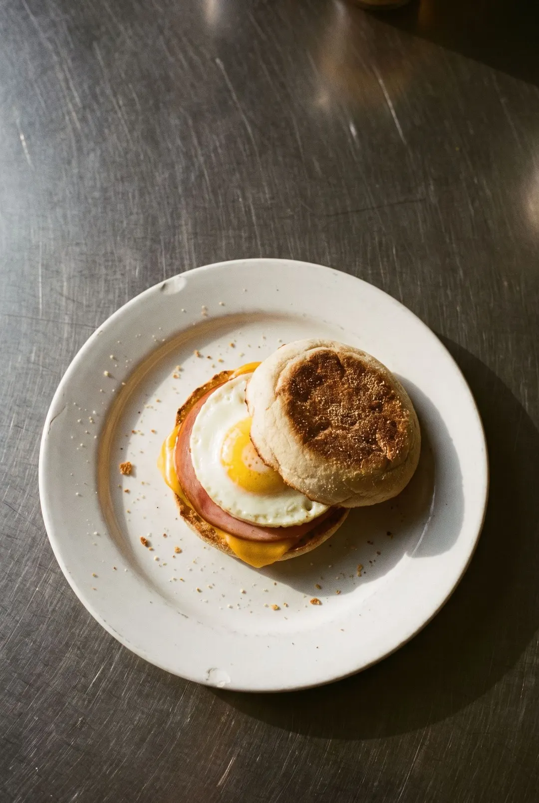A toasted English muffin with a round egg on a white plate