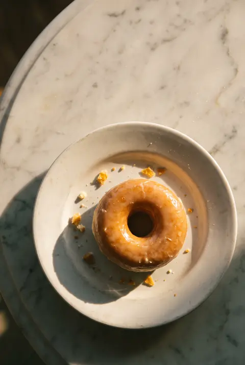 A glazed ring doughnut on a white plate
