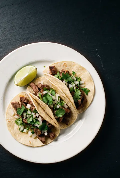 Three soft tacos with meat on a white plate
