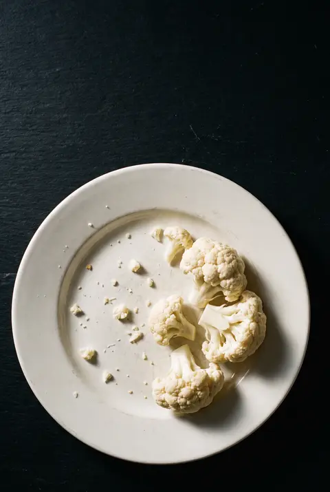 A few raw cauliflower florets on a white plate