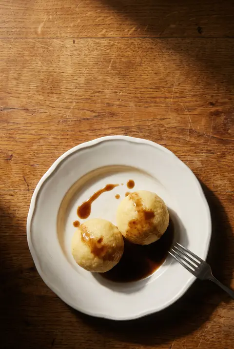 Two potato dumplings with a little gravy on a white plate