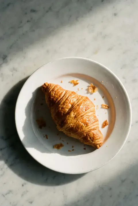 A golden butter croissant on a white plate