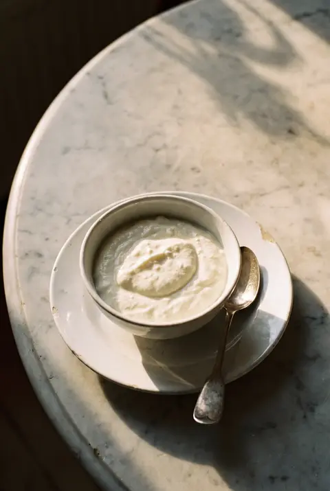 250 g of thick white quark in a white porcelain bowl on a white plate