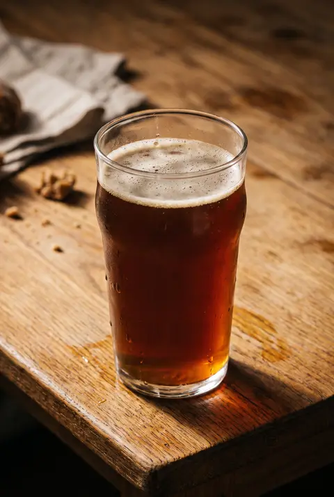 Half a litre of dark amber kvass with a thin foam in a beer glass