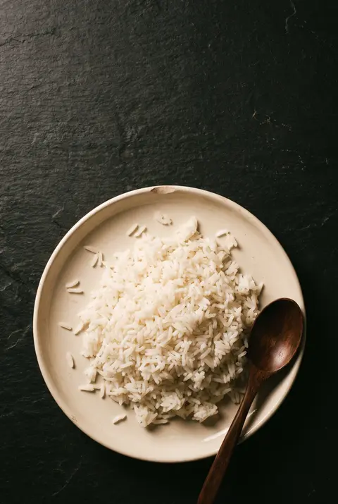 A full plate of cooked white rice on a white plate