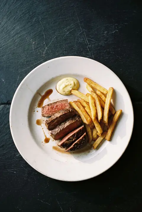 A plate of steak frites on a white plate
