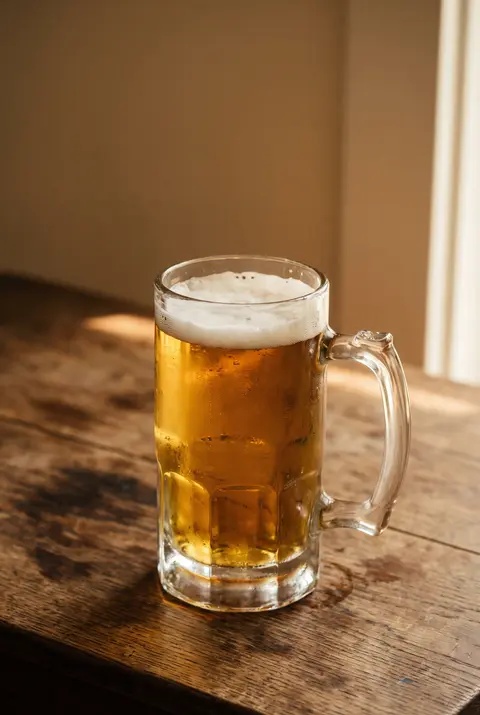 A full litre of golden Oktoberfest beer with a thick white head in a glass beer stein