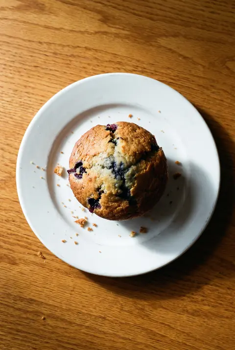 A big bakery blueberry muffin with a domed top on a white plate