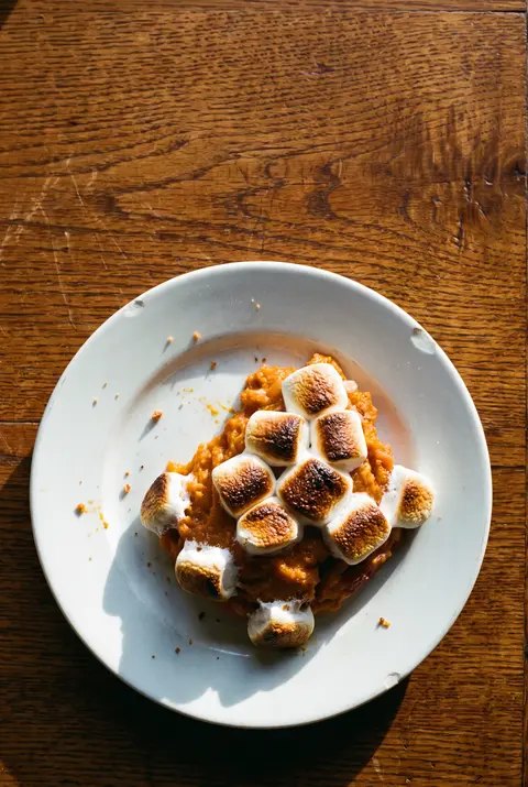 A side portion of sweet potato casserole with toasted marshmallows on top on a white plate