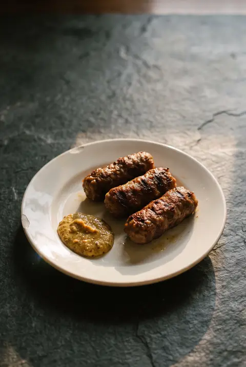 Three grilled mici on a white plate