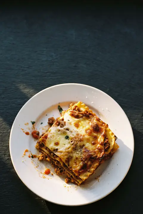 A restaurant portion of lasagne showing its layers of pasta on a white plate