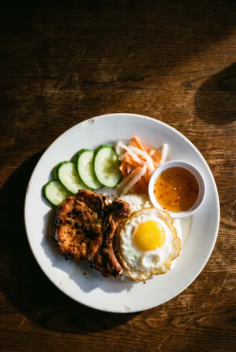 Vietnamese broken rice with a grilled pork chop on a white plate
