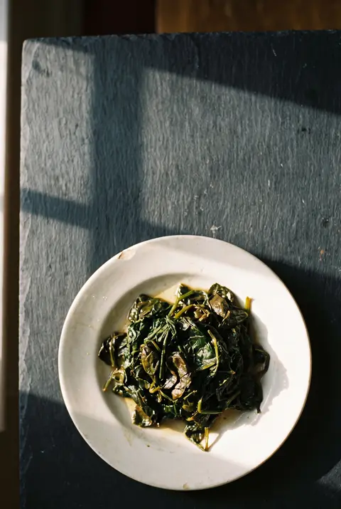 A portion of wilted cooked spinach on a white plate
