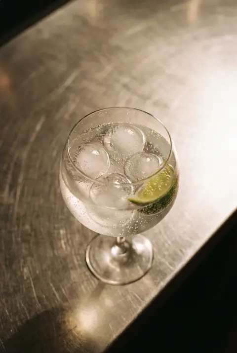 A gin and tonic with ice in a balloon glass