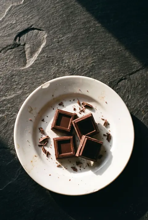 Four squares of dark chocolate on a white plate