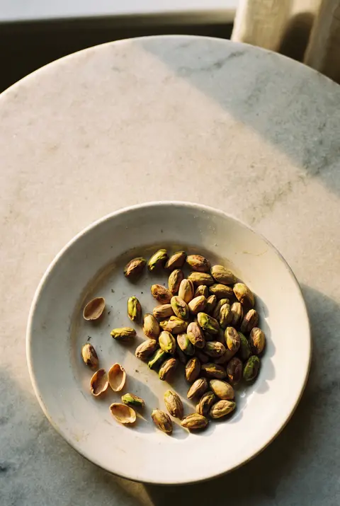 A small heap of shelled pistachios on a white plate