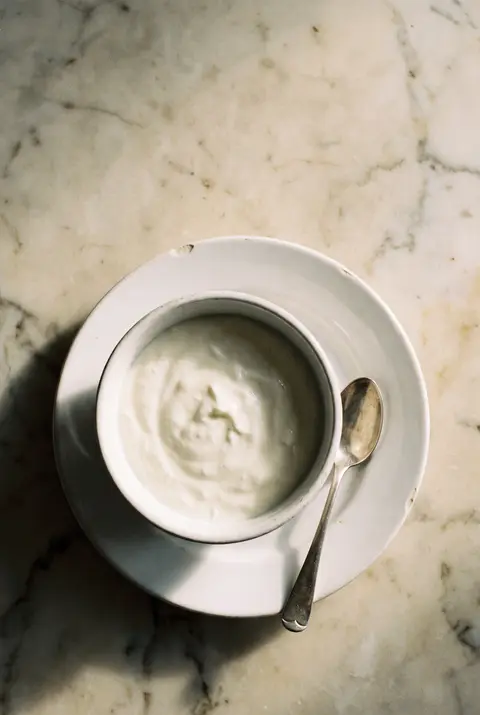 A white porcelain bowl of thick plain skyr on a white plate