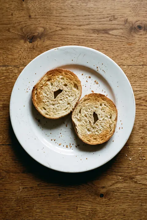 A plain bagel cut in half on a white plate