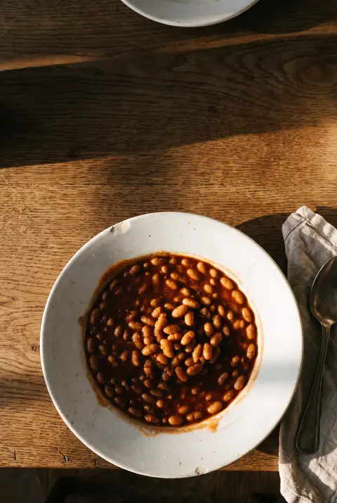 Half a tin of baked beans in tomato sauce on a white plate