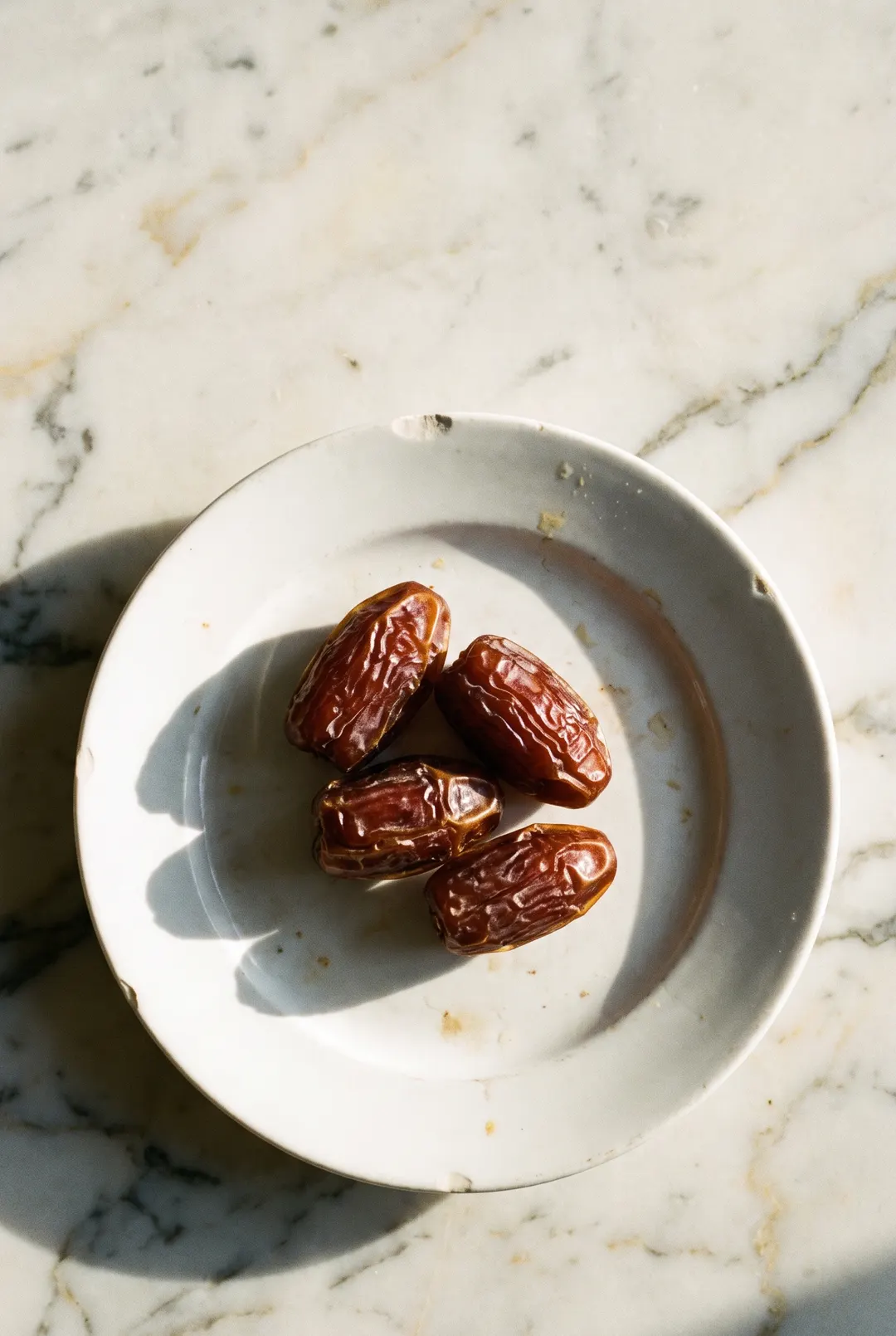 Three soft Medjool dates on a white plate