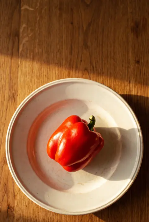 A whole red pepper on a white plate