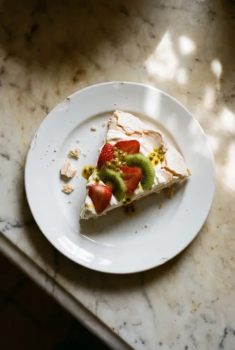 A slice of pavlova with whipped cream on a white plate