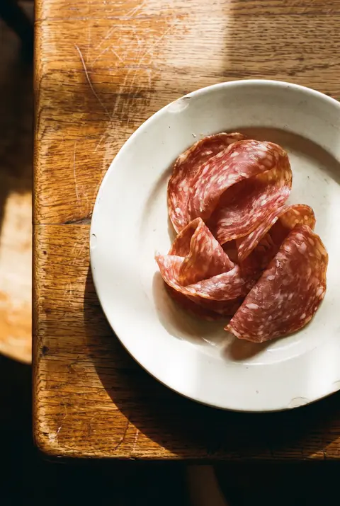 A few thin slices of salami on a white plate