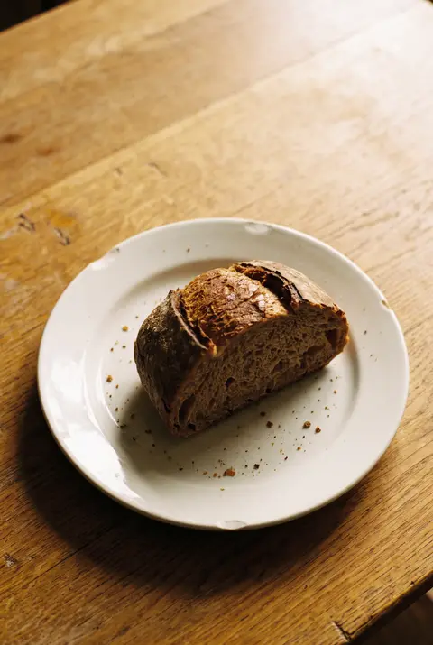 A medium slice of brown sourdough bread on a white plate