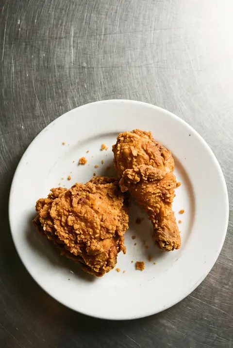 Two pieces of crisp fried chicken on the bone on a white plate