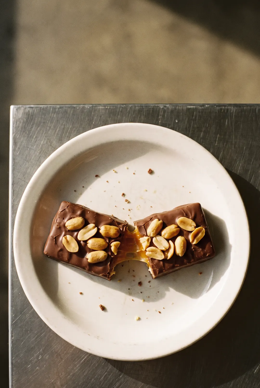 A chocolate bar with caramel and peanuts on a white plate